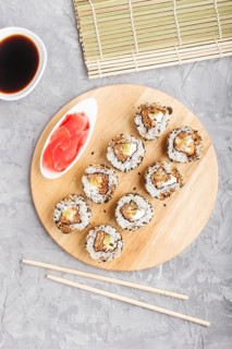 Japanese maki sushi rolls with salmon, sesame, cucumber chopsticks, soy sauce and marinated ginger