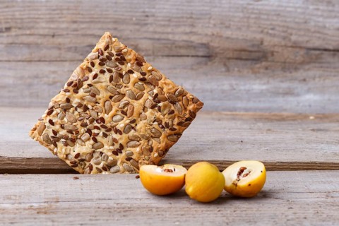 Biscuits with flax, sesame and sunflower seeds and yellow quince fruit on a rustic wooden