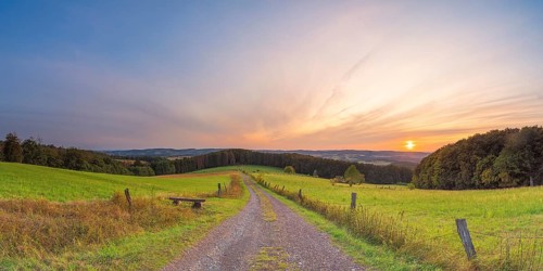 A small bench stands at the edge of a path with a view of the Weserbergland, landscape format,