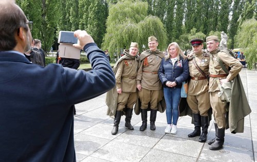Men in Russian uniforms take a group photo at the Soviet memorial in Treptow Park to mark the 74th