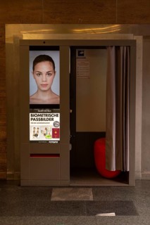 A photo booth for biometric passport photos with a female face on the advertising poster,