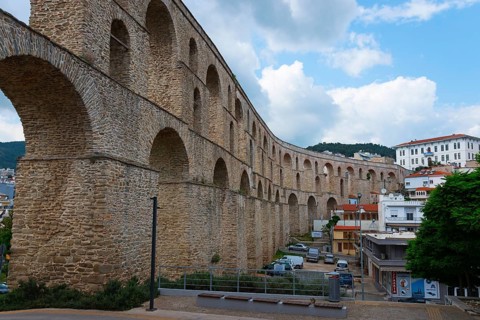 A Roman aqueduct spans a modern cityscape under a cloudy sky, Kavala, Dimos Kavalas, Eastern
