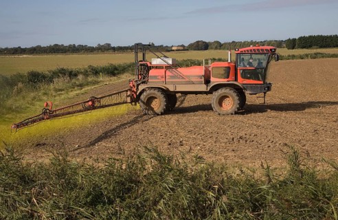 Farm machinery spraying Glyphosate herbicide on an arable field near Hollesley, Suffolk, England,