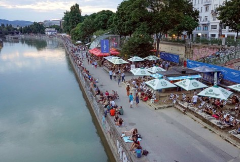 People relaxing in summer temperatures on the banks of the Danube Canal in Vienna, 19 July 2019