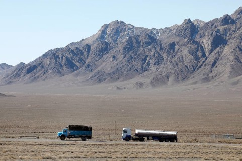 An old round-hood Mercedes truck in front of a new Mercedes truck on a motorway in the central