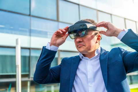 Close-up with copy space of a serious businessman using a virtual reality headset outside a modern