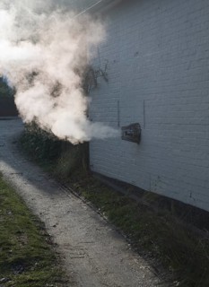 Heat steam emissions from domestic oil powered boiler heating system released through wall of house
