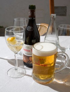 Beer and iced water glasses and wine bottle on restaurant table in Spain