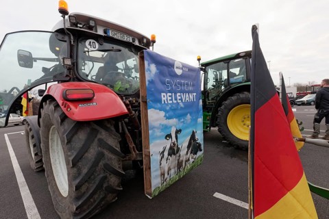Poster with dairy cows and writing Systemrelevant on a tractor, farmer protests, demonstration