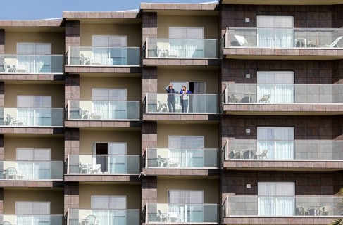 An elderly couple looks out from a balcony of an apartment complex in Torremolinos, Costa del Sol,