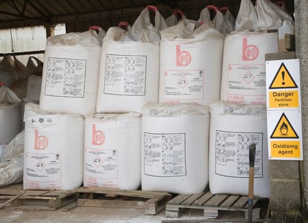 Danger fertiliser store oxidising agent sign Ammonia Nitrate bags in barn, Suffolk, England, United