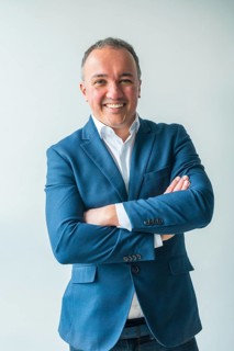 Vertical three quarter length studio portrait of a confident businessman standing proud with arms