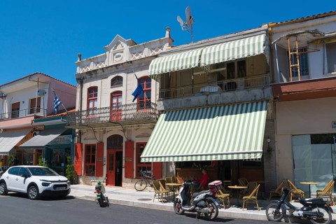 Traditional buildings on a sunny street with parked cars and motorbikes, Museum of Silk Art,