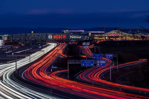 A8 motorway at Stuttgart Airport with Bosch multi-storey car park in the evening, cars create light