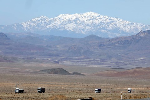 Truck on a motorway in the central desert of Iran, snow-capped mountains can be seen in the