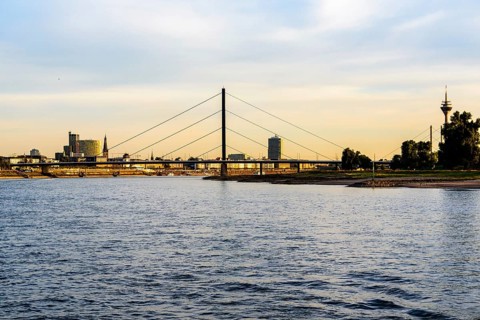 View of a city with a suspension bridge over a river at dusk, Theodor-Heuss-Bruecke, Duesseldorf,