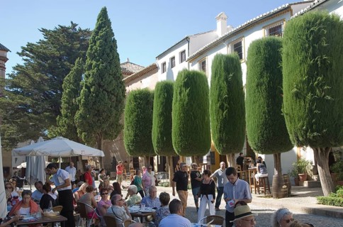 Groups of people sitting at tables and chairs of outdoor street cafe in the old city of Ronda,