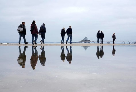Walkers reflected in the water on the beach in Heringsdorf, Usedom Island, 21/09/2019