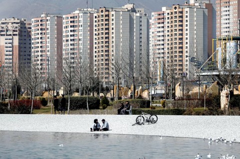 A young couple sits on the beach of Lake Chitgar in Tehran, Iran. Lake Chitgar is a man-made lake