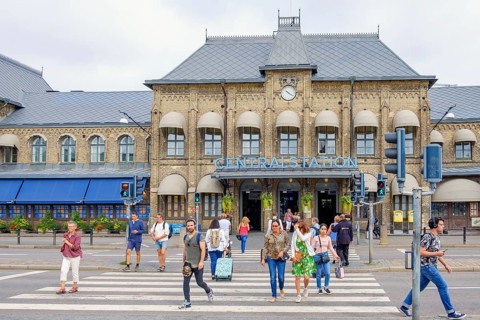 Railway station in Gothenburg with people crossing a city street at the pedestrian crossing,