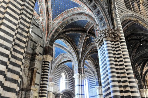 The nave of the cathedral with its black and white striped marble columns, cross and round arches,