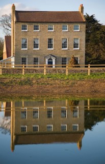 High House Farm farmhouse reflected in water of newly dug pond, Bawdsey, Suffolk, England, United