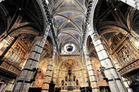 The nave of the cathedral with its black and white striped marble columns, cross and round arches,