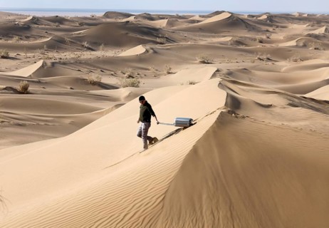 Symbolic image, tourist with suitcase in the desert, Mesr Desert, Iran. The Mesr Desert is part of