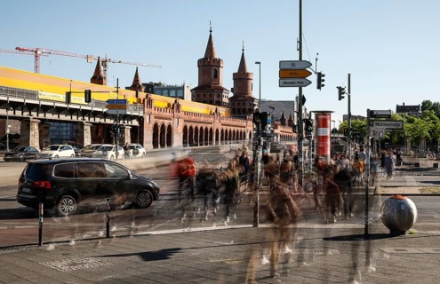 Long exposure shows underground train on the Oberbaum Bridge and people crossing a street, Berlin,
