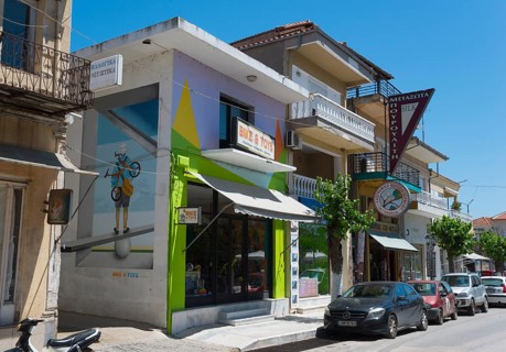 Modern building with a colourful facade and parked vehicles on the roadside, commercial street,