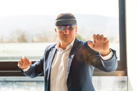 Frontal view of a businessman wearing mixed reality goggles touching interactive screen in the