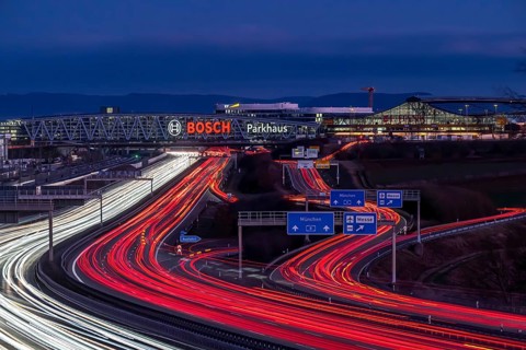 A8 motorway at Stuttgart Airport with Bosch multi-storey car park in the evening, cars create light
