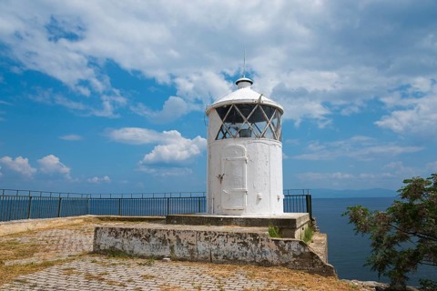 White lighthouse at the edge of a coast with cloudy sky in the background, old town, Kavala, Dimos