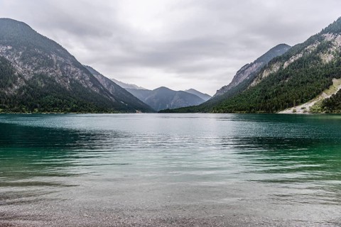 A peaceful lake surrounded by mountains under a cloudy sky, Plansee, Heiterwang, Tyrol, Austria,