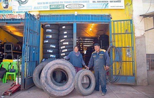 Peruvian couple, 38 and 45 years old, showing tyres from their tyre workshop, Palccoyo, Checacupe