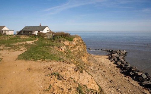 Cliff top buildings at risk of coastal erosion, Happisburgh, Norfolk, England with beach rock