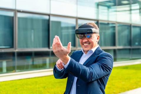 Happy adult caucasian businessman smiling while wearing mixed reality glasses outside a financial