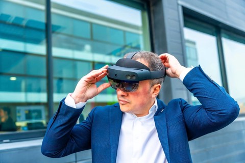 Businessman wearing augmented reality futuristic and innovative goggles outside a financial
