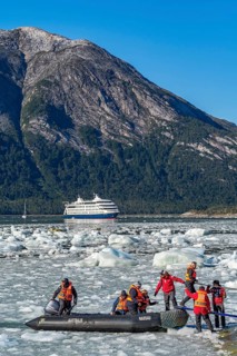Passengers of the cruise ship Stella Australis land in a rubber dinghy between ice floes on the Pia