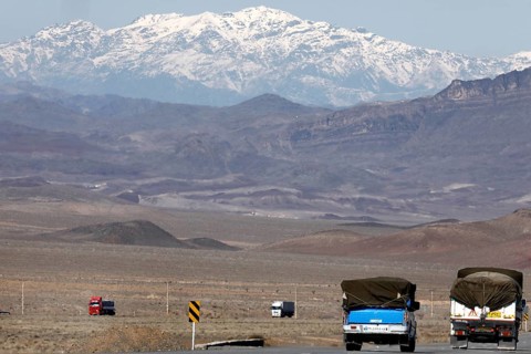 Truck on a motorway in the central desert of Iran, snow-capped mountains can be seen in the