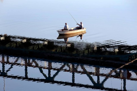 Anglers cast their rods from a boat under a bridge reflected in the Oder, Mescherin, 13 October