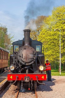 Old steam locomotive at a railway station with a driver outside the locomotive, Sweden, Europe
