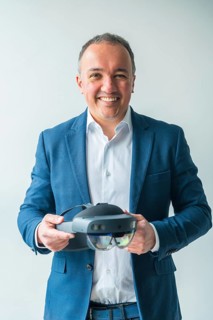 Vertical studio portrait with grey background of a confident businessman holding a futuristic mixed