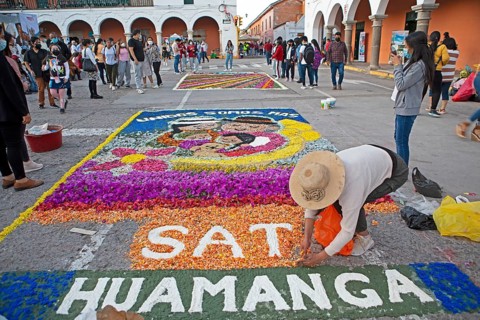 Peruvian woman making a floor painting in the Plaza de Armas, spectators watching, Ayacucho,