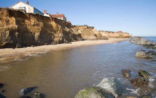 Cliff top buildings at risk of coastal erosion, Happisburgh, Norfolk, England rock armour boulders