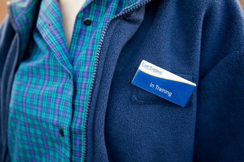 Model released teenage girl in uniform for her job in a Co-operative shop, UK wearing a badge