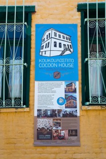 Informative plaque on a yellow wall advertising a cultural centre or museum, sign at Koukoulospito,
