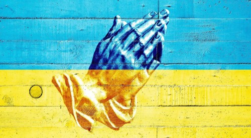 Ukrainian flag painted on a concrete wall with praying hands