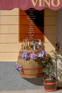 A wine barrel serves as a display area for bottles in front of a souvenir shop under warm sunlight,