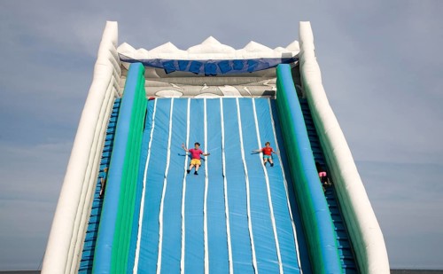 Children playing on giant inflated slide seaside attraction, Great Yarmouth, Norfolk, England,